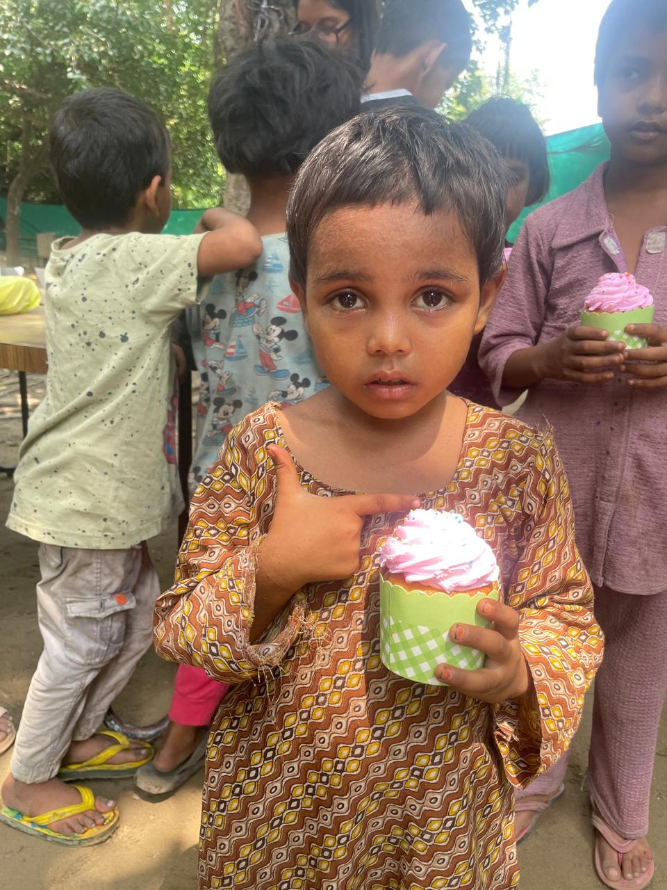 A child pointing proudly at her cupcake